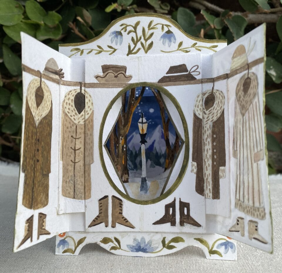a small paper tunnel book depicting the wardrobe from 'The Chronicles of Narnia,' which opens up to reveal the lamp post and winter scene